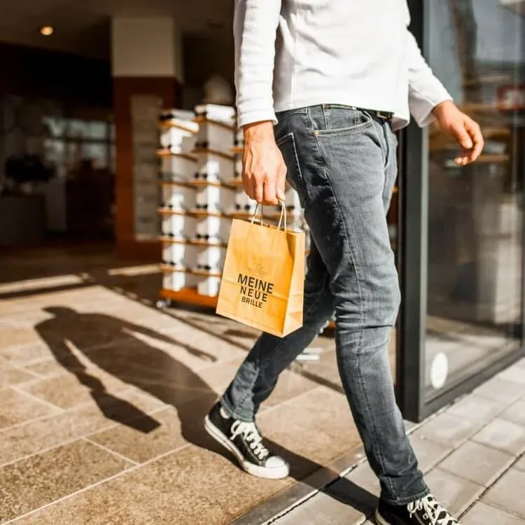 Ein Kunde verlässt den Laden mit einer Tüte in der Hand. Die Tüte trägt die Aufschrift: Reiffert Augenoptik - Meine neue Brille.